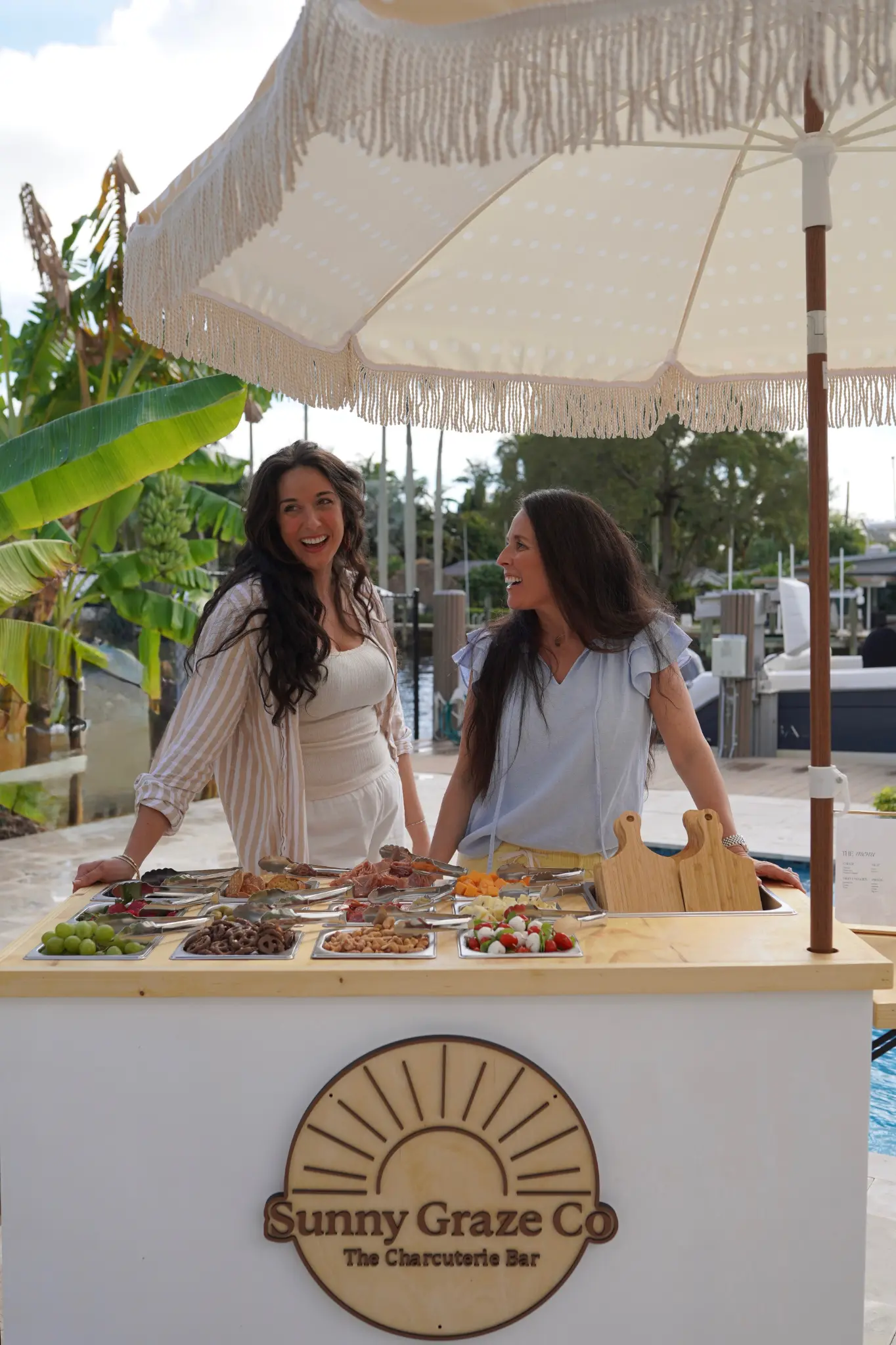 Two women hosting and presenting a grazing table outdoors